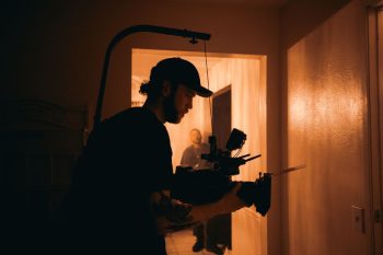 Estudiante de cine con cámara en mano, filmando una escena. Crédito: Canva.